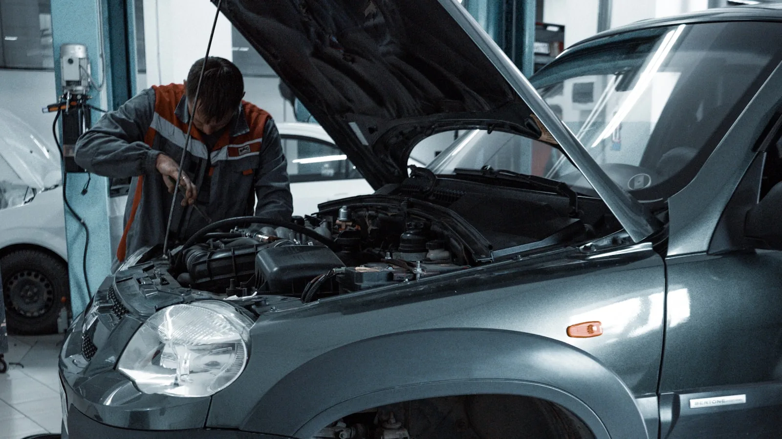 Mecanic la capota deschisă a unui SUV într-un service, treabă de lichid de frână sub capotă