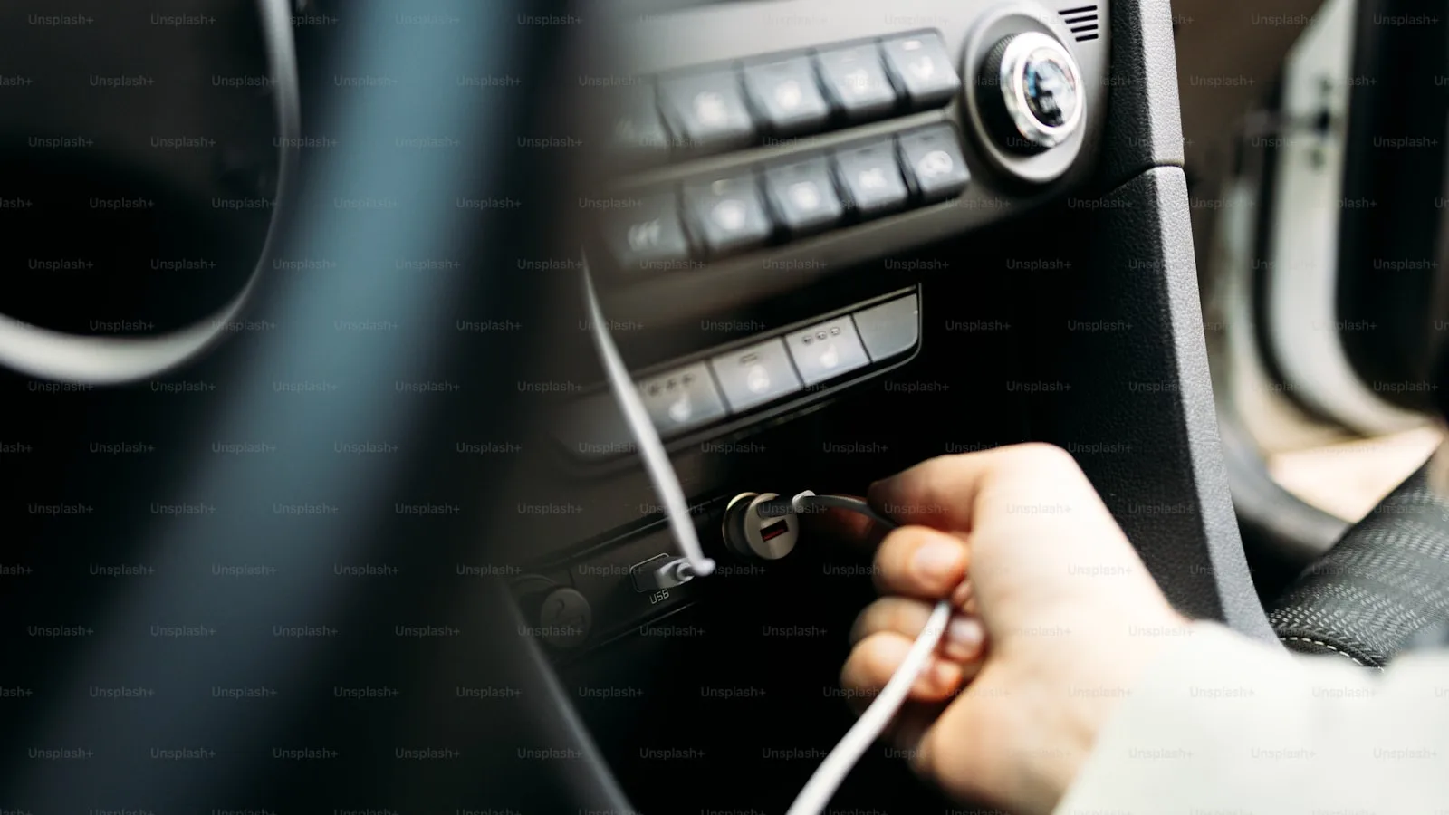 Mână care conectează încărcător USB în priza auto 12V de pe consolă